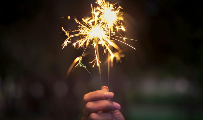 A hand holding sparklers glowing brightly in a dark night, capturing the essence of celebration.