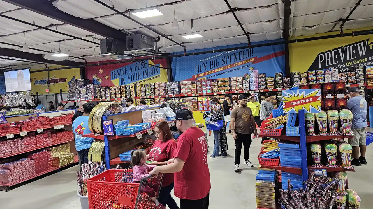 Family filling a red shopping cart inside an Alamo Fireworks store
