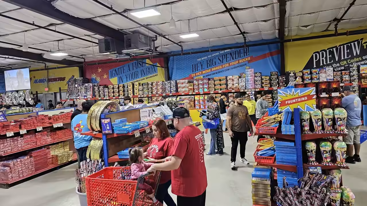 Family filling a red shopping cart inside an Alamo Fireworks store
