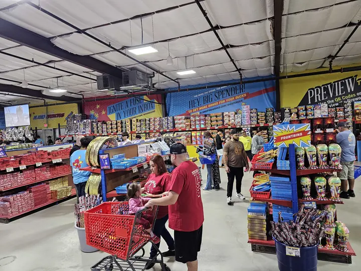 Family filling a red shopping cart inside an Alamo Fireworks store