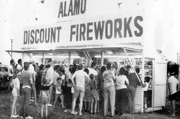 Vintage black and white photo of a crowd at an Alamo Discount Fireworks stand