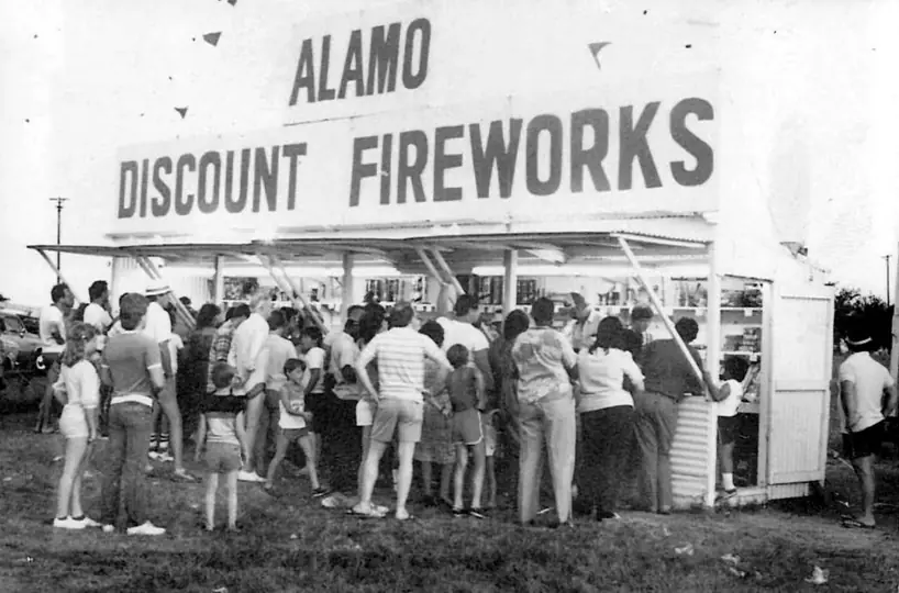 Vintage black and white photo of a crowd at an Alamo Discount Fireworks stand