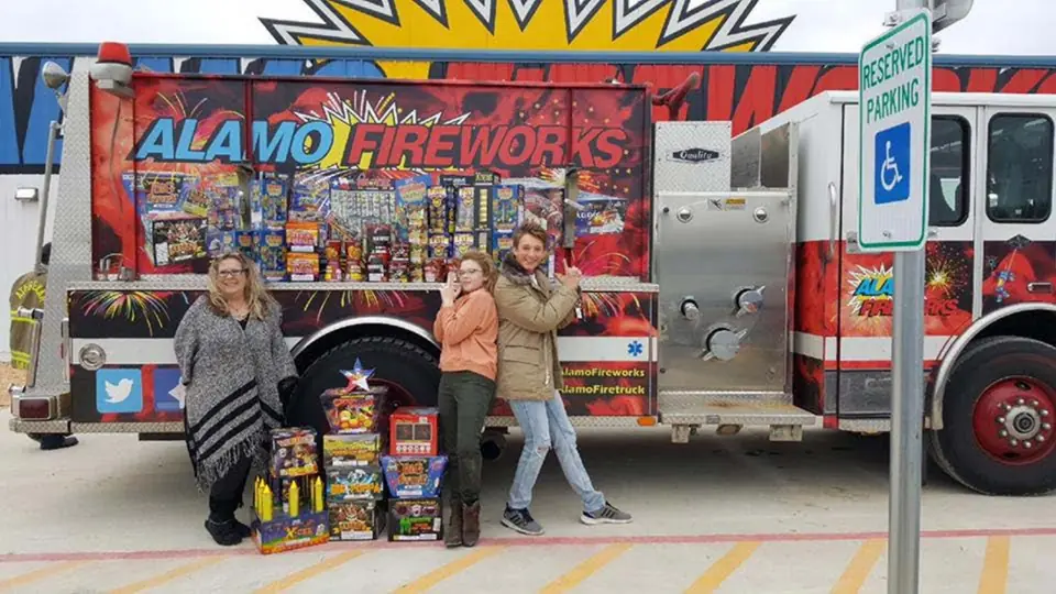 Customers posing with their fireworks in front of the Alamo Fireworks fire truck