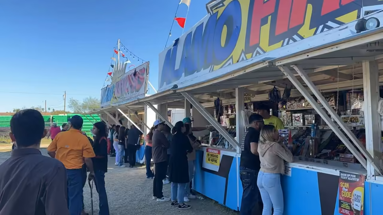 Customers lined up at an Alamo Fireworks stand on a sunny day