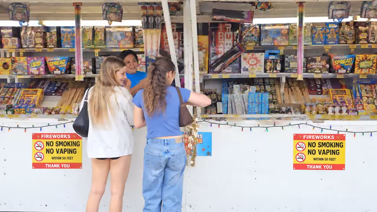 Two girls choosing fireworks at an Alamo Fireworks stand