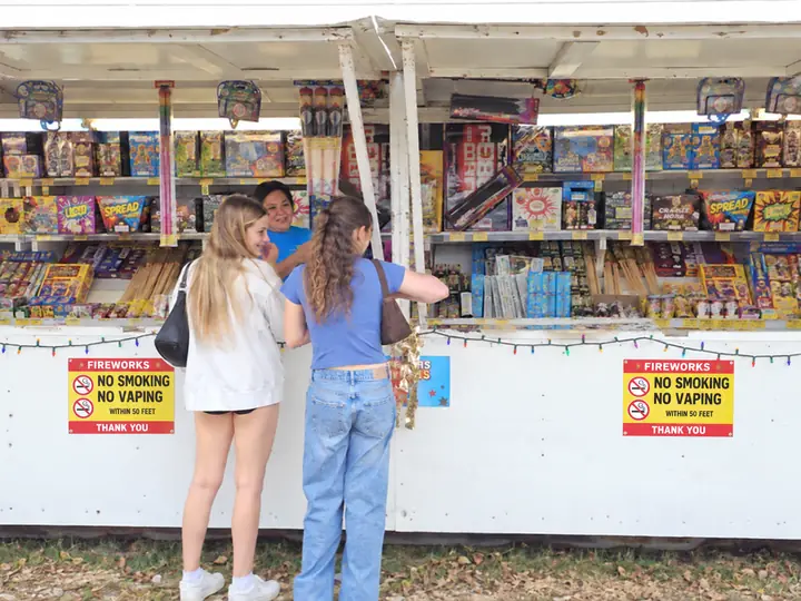 Two girls choosing fireworks at an Alamo Fireworks stand